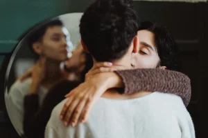 Pareja abrazándose en un momento íntimo reflejada en un espejo