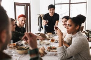 fotografía de amigos sonriendo y compartiendo una comida en una mesa