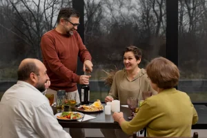 grupo de adultos compartiendo comida y vino en una mesa