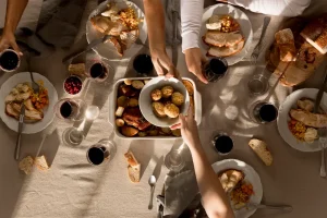 fotografía cenital de personas compartiendo una comida con vino y pan.