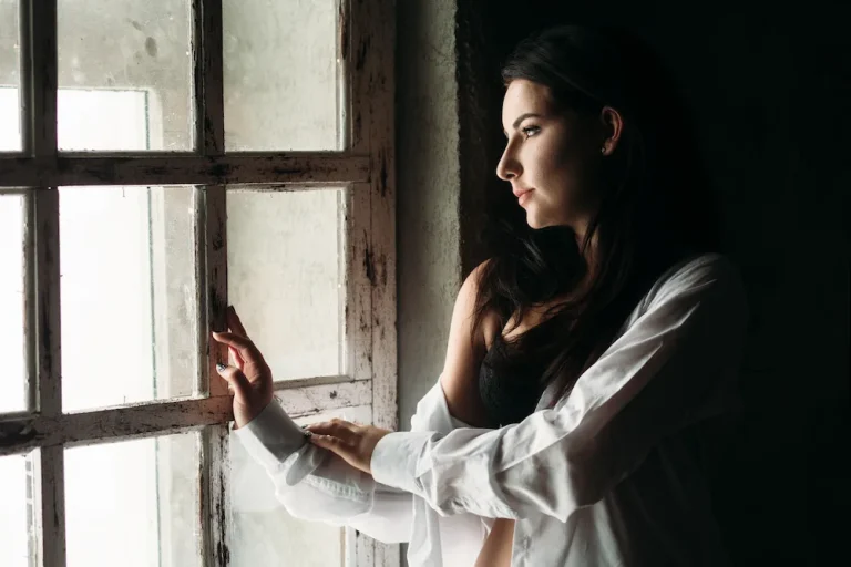mujer sonriendo cálidamente mientras mira por la ventana