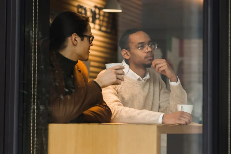 dos personas conversando con actitud pensativa en una cafetería